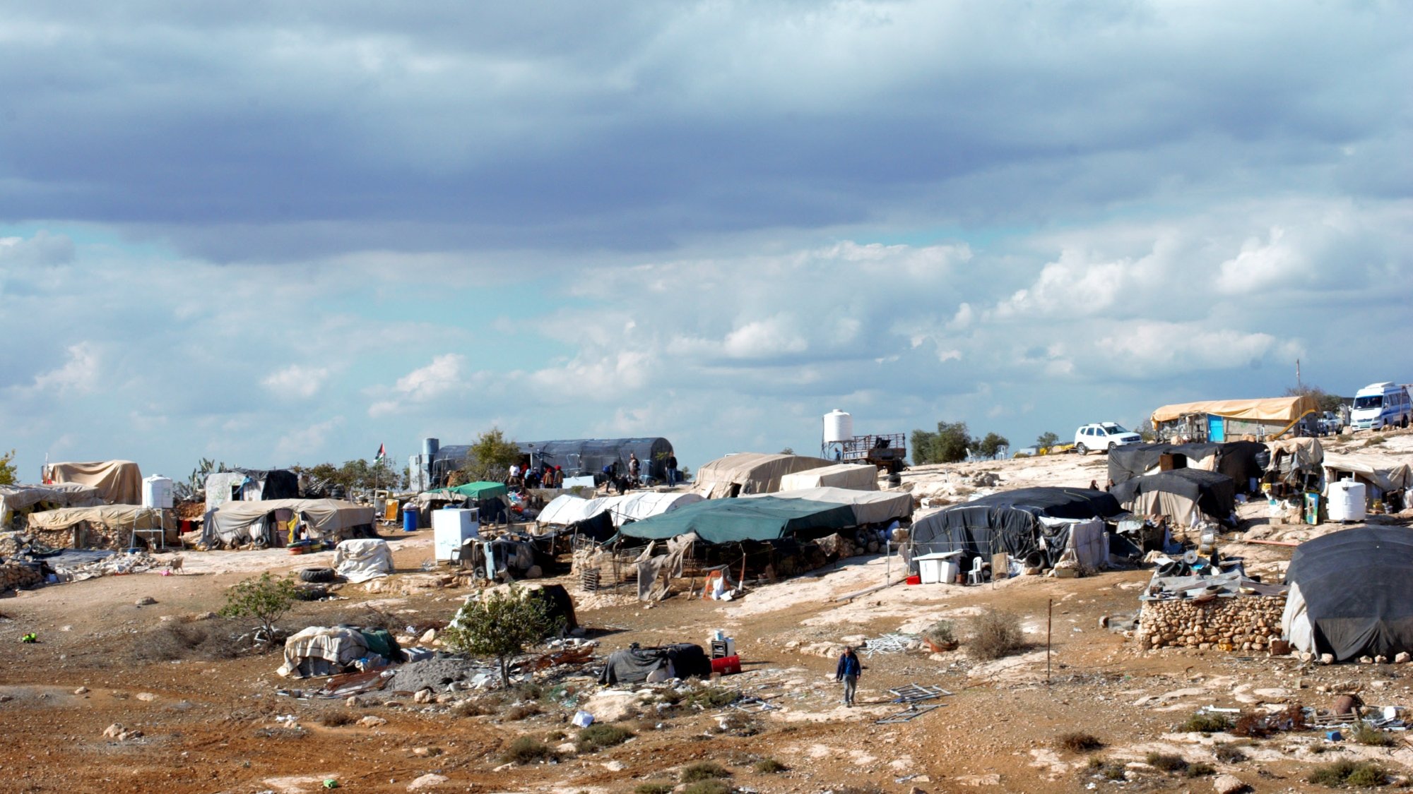 Des tentes éparses sur un terrain rocky, sous un ciel nuageux.