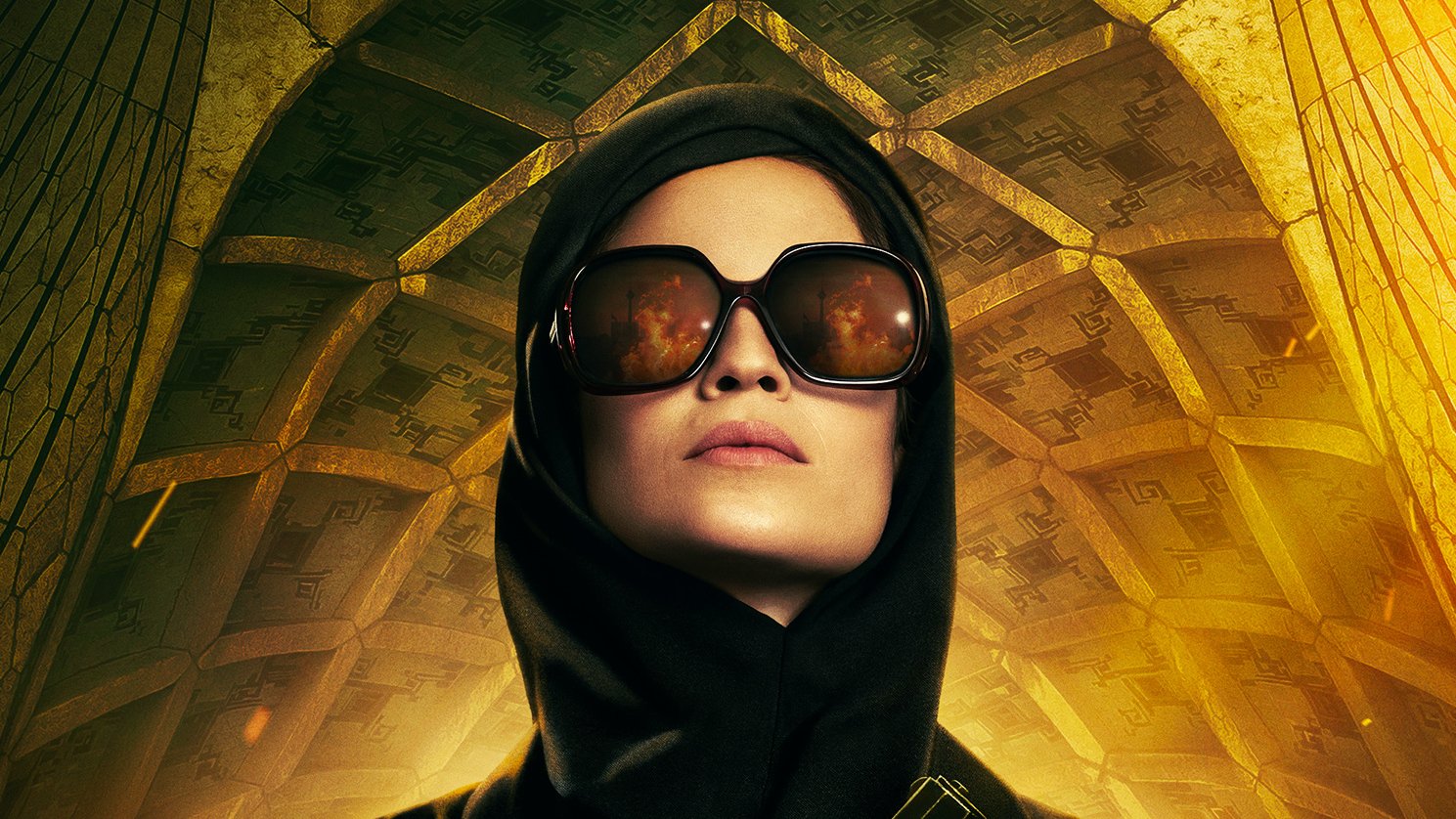 L'image présente une femme au regard déterminé, vêtue d'une tenue noire élégante. Elle porte de grandes lunettes de soleil qui reflètent une lumière vive. Son visage est partiellement caché par un foulard sombre. Elle tient une arme à feu à la main, ce qui suggère une ambiance de tension ou d'action. En arrière-plan, on distingue une architecture impressionnante avec des motifs géométriques qui ajoutent une dimension dramatique à la scène. Les couleurs chaudes, principalement le jaune et l'or, accentuent l'atmosphère intense de l'image.