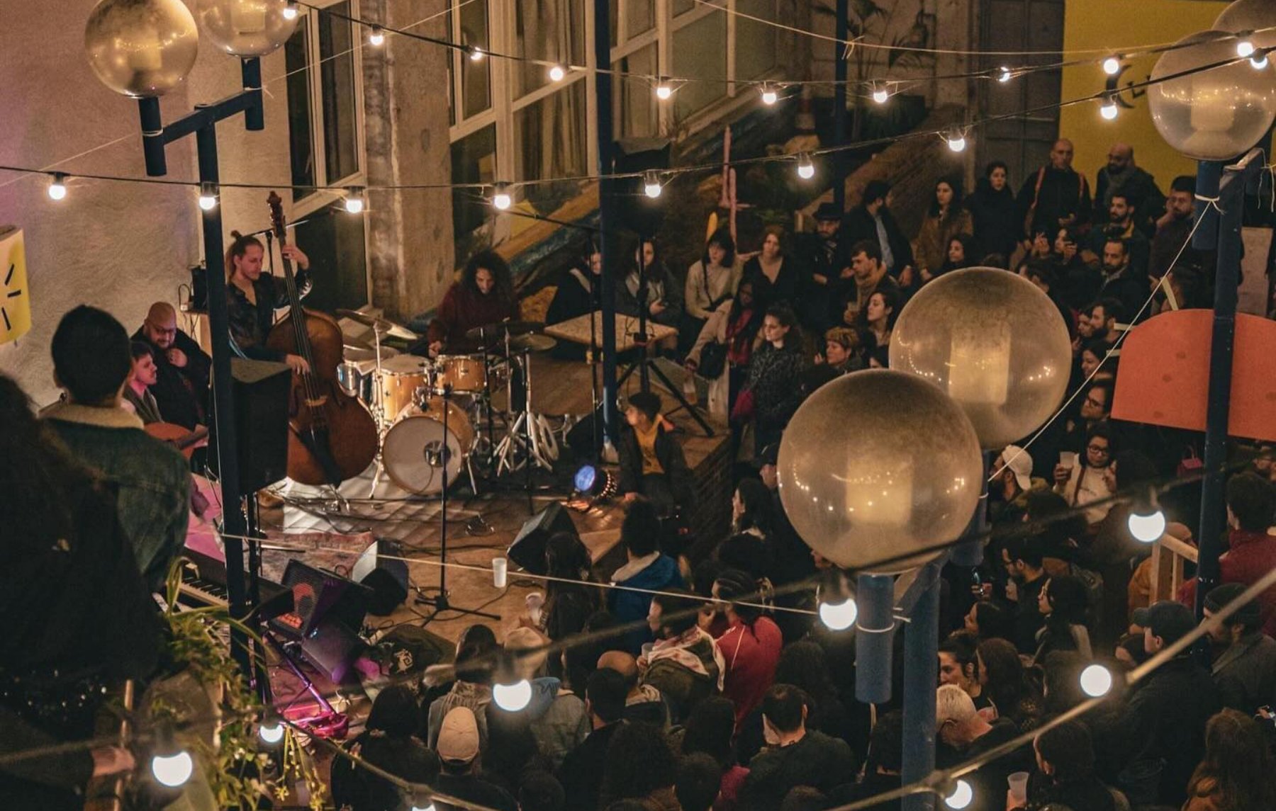 Concert animé dans un lieu chaleureux, éclairé par des guirlandes lumineuses.
