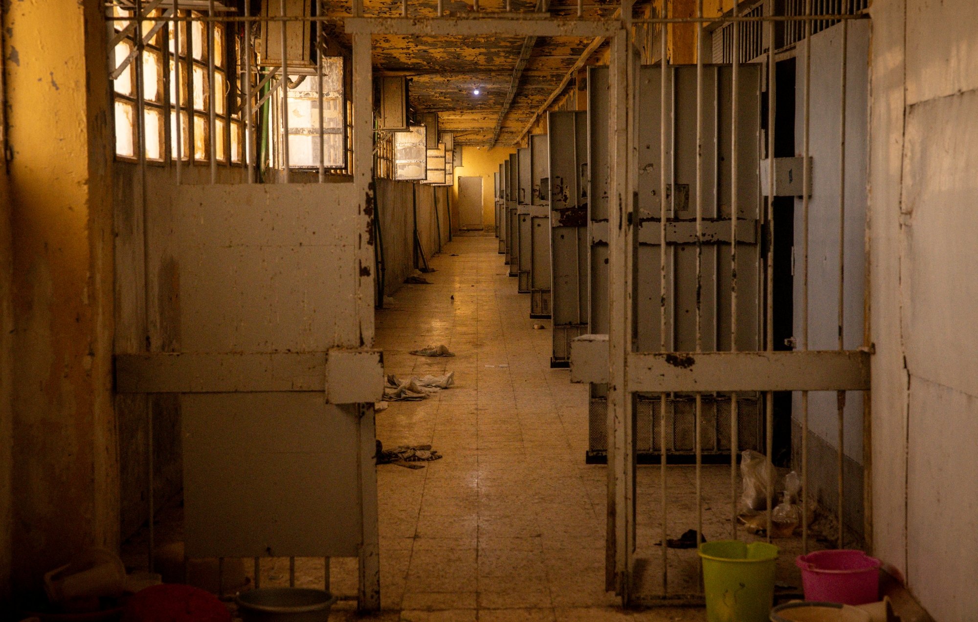Couloir désert d'une structure, avec des cages vides et des murs en détérioration.