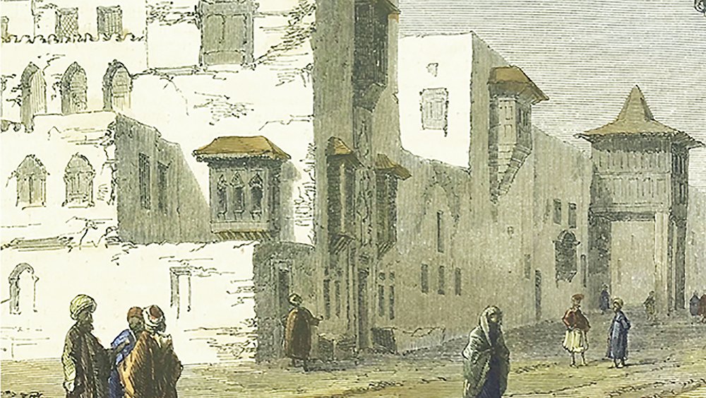 L'image montre une scène urbaine dans un style architectural traditionnel. On peut voir des bâtiments à plusieurs étages avec des balcons et des fenêtres typiques, dont certaines semblent être en ruine. Des personnes marchent dans la rue, certaines en groupes, d'autres seules, vêtues de vêtements traditionnels. L'ambiance de l'image évoque une période historique, probablement dans un contexte orientale ou méditerranéen, avec des couleurs douces et une lumière naturelle. Le paysage est urbain, avec des détails architecturaux qui témoignent d'un passé riche.