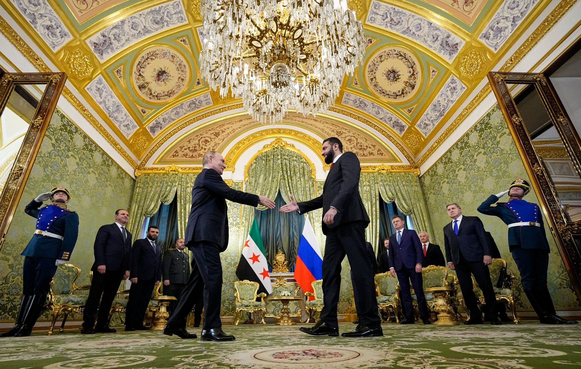 Réunion officielle dans une salle luxueuse, avec des drapeaux et des personnes en uniforme.