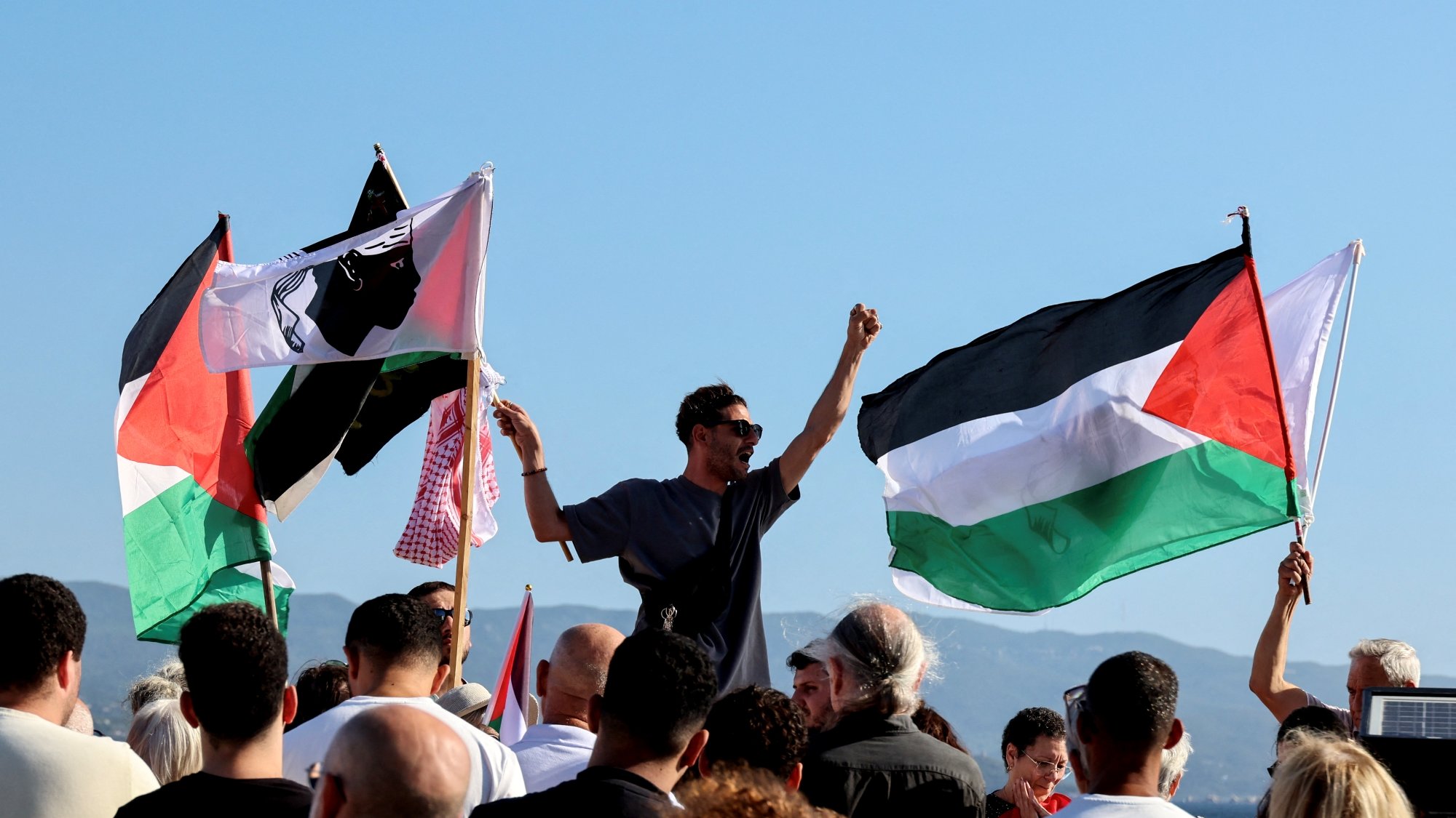 Manifestation avec des drapeaux palestiniens et des personnes rassemblées, exprimant leur soutien.