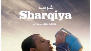 L'image représente une scène d'un film intitulé "Sharqiya", réalisé par Ami Livne. On y voit un homme portant un pot en plastique, semblant s'hydrater en plein air. Le décor suggère un paysage rural, avec quelques animaux en arrière-plan. L'expression de l'homme pourrait évoquer une recherche de répit ou un moment de pause dans un environnement quotidien.