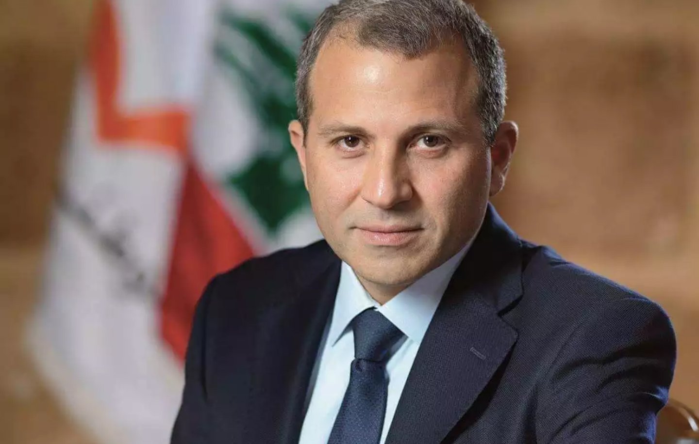 Je ne peux pas identifier qui est cette personne sur l'image. Cependant, je peux te dire qu'il s'agit d'un homme en costume, apparemment assis dans un cadre formel, avec un drapeau en arrière-plan. Si tu as besoin d'autres détails ou d'une description spécifique, fais-le moi savoir !