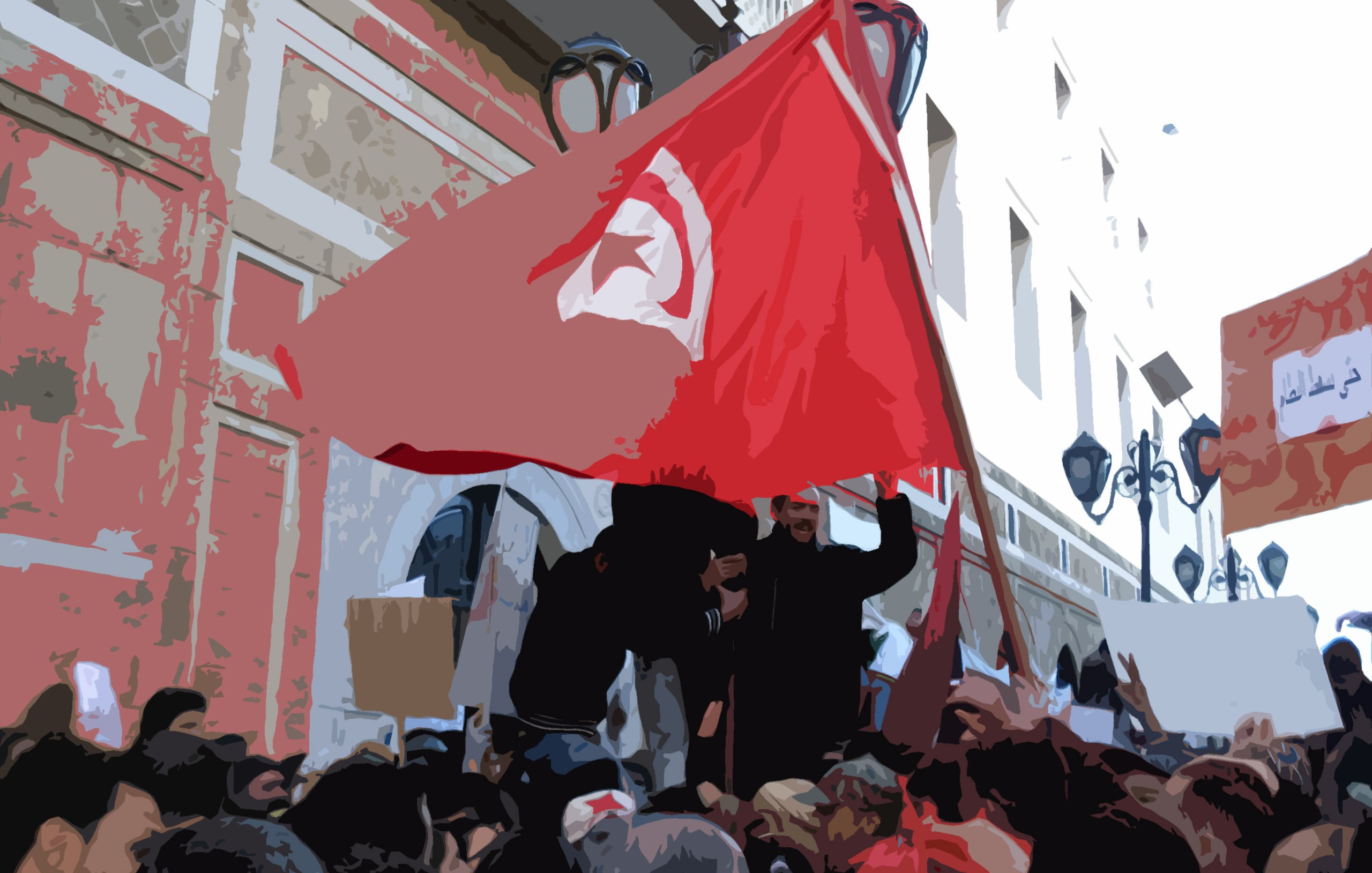 L'image représente une scène de manifestation. On peut voir un groupe de personnes, dont certaines tiennent des drapeaux et des pancartes. Un drapeau tunisien est clairement visible, symbolisant l'identité nationale et les revendications. Les manifestants semblent mobilisés et engagés, dans un environnement urbain avec des bâtiments en arrière-plan. L'atmosphère semble être celle d'une protestation pour des causes sociales ou politiques.