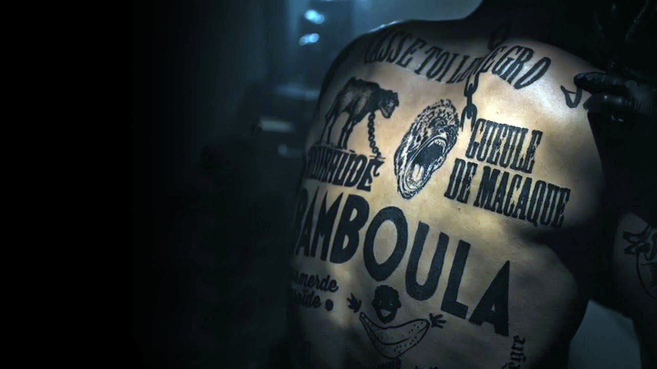 Cette image montre un dos humain couvert de tatouages. Les inscriptions et les illustrations incluent des éléments comme des animaux, des mots en lettres majuscules, et des motifs graphiques. L'éclairage semble sombre, ce qui met en valeur les détails des tatouages. L'ambiance générale est à la fois artistique et intense.