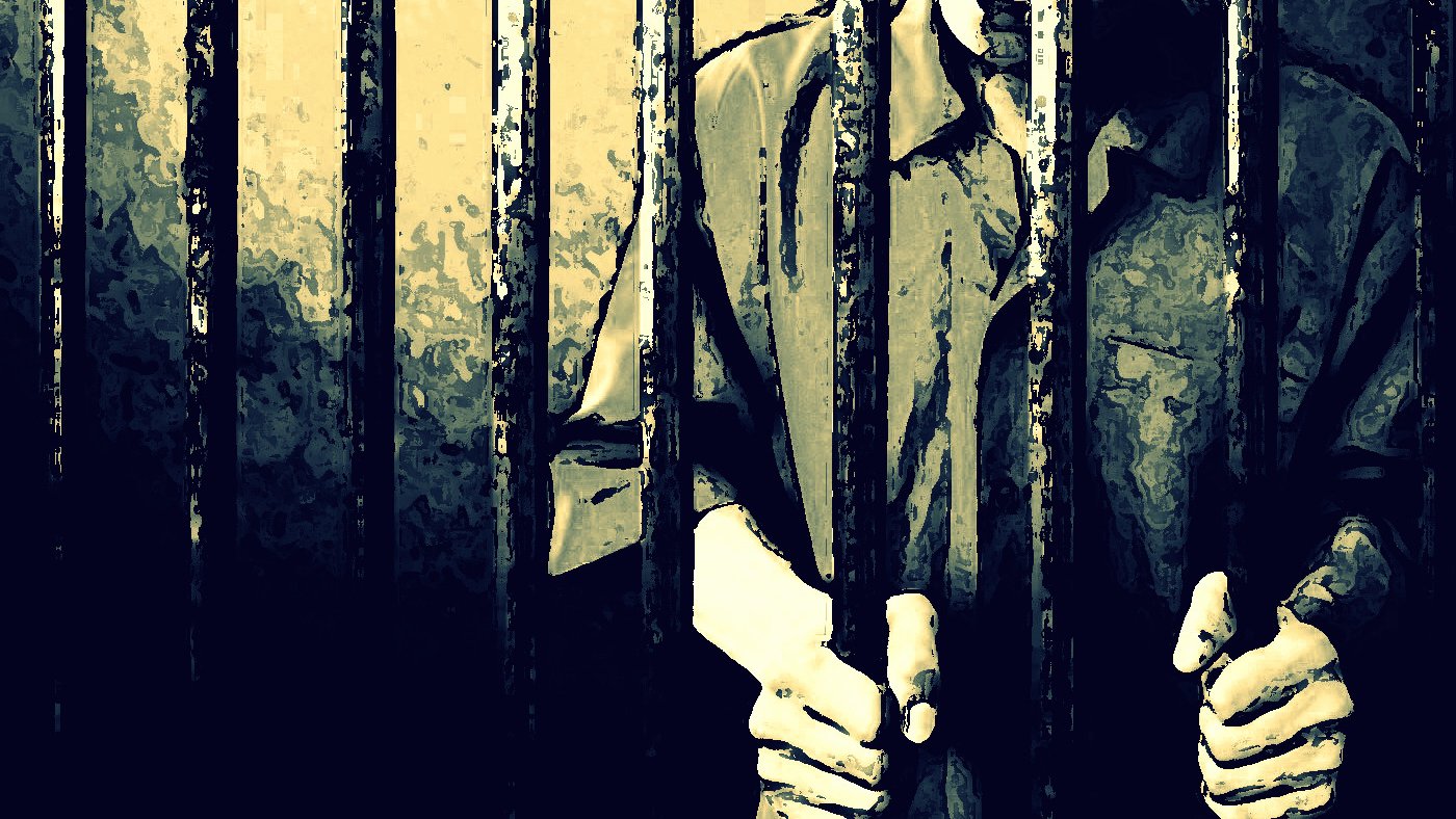 L'image montre une silhouette humaine derrière des barreaux, illustrant une ambiance de détention ou d'emprisonnement. Les mains de la personne sont visibles, agrippant les barreaux, ce qui renforce le sentiment d'enfermement. L'éclairage est sombre, mettant en avant les barres de fer, et l'atmosphère générale évoque des émotions telles que la solitude ou l'abandon.