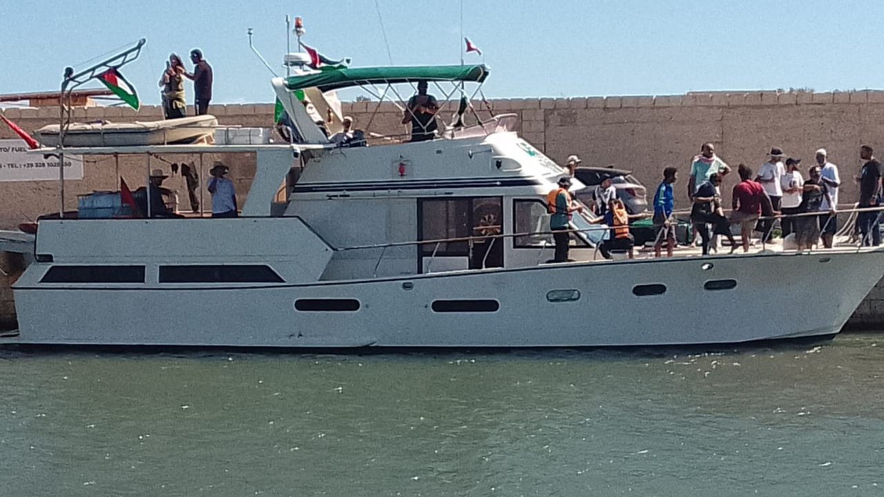 Un bateau à moteur blanc à quai, avec des passagers et un ciel bleu.