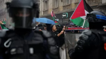 Manifestation avec des drapeaux palestiniens, policiers en tenue anti-émeute, ambiance tendue.