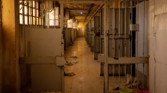 Couloir désert d'une structure, avec des cages vides et des murs en détérioration.