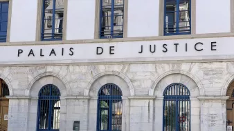 Façade d'un bâtiment imposant avec l'inscription "Palais de Justice" et des fenêtres à arcs.