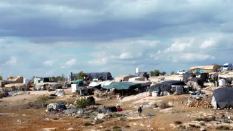 Des tentes éparses sur un terrain rocky, sous un ciel nuageux.