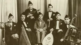 Groupe de musiciens en costume noir, instruments variés, ambiance d'époque.