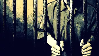 L'image montre une silhouette humaine derrière des barreaux, illustrant une ambiance de détention ou d'emprisonnement. Les mains de la personne sont visibles, agrippant les barreaux, ce qui renforce le sentiment d'enfermement. L'éclairage est sombre, mettant en avant les barres de fer, et l'atmosphère générale évoque des émotions telles que la solitude ou l'abandon.