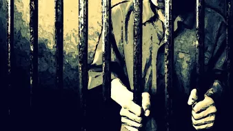 L'image montre des barreaux de prison, avec des mains qui s'agrippent à eux. Le fond est sombre et évoque une atmosphère de confinement. La personne derrière les barreaux est en partie visible, portant une chemise qui semble typique des uniformes de prison. L'éclairage crée des ombres, accentuant le sentiment d'isolement et de détention.