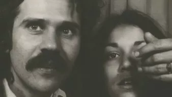 Un homme avec une moustache et une femme montrant un doigt vers l'objectif.