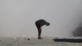 Un homme âgé se penche, entouré de débris et de poussière.