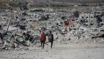 Deux personnes marchent dans un paysage de destruction, entourées de débris.