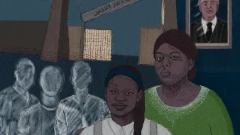 L'image montre deux femmes, l'une portant une chemise blanche et l'autre un pull vert, partageant un moment de solidarité. En arrière-plan, on voit des silhouettes floues qui semblent représenter des personnes en attente, tandis qu'une grande affiche indique "جمعية دعم اللاجئين" (Association de soutien aux réfugiés). Au-dessus, un portrait d'un homme, probablement une figure importante, est accroché au mur. Les couleurs de l'image et les expressions des femmes transmettent une atmosphère de courage et de soutien dans un contexte difficile.