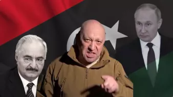 L'image présente un homme au premier plan, portant une veste kaki et exprimant visiblement une émotion forte. En arrière-plan, il y a des drapeaux, notamment un drapeau libyen avec des couleurs rouge, noir, et vert, ainsi qu'une étoile et un croissant. De chaque côté de l'homme, on peut voir deux silhouettes ou visages flous, qui représentent probablement des figures politiques. L'atmosphère de l'image semble tendue, avec des éléments visuels qui suggèrent un contexte politique ou militaire.