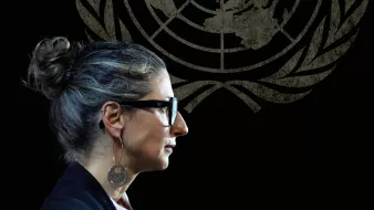 Femme avec des lunettes, coiffure en chignon, silhouette sur fond du logo de l'ONU.