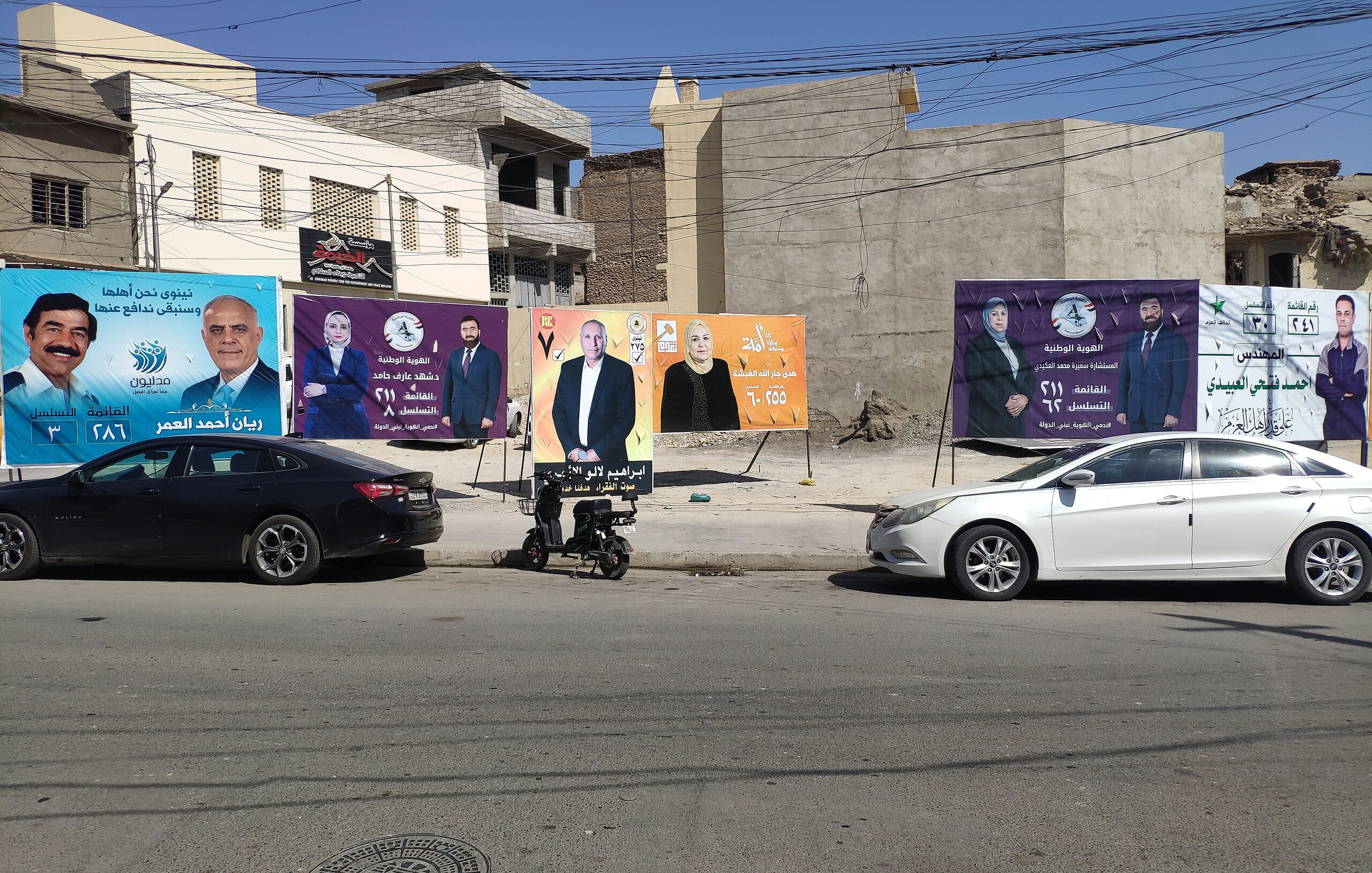 Una strada con diversi manifesti pubblicitari colorati su un muro di fondo.