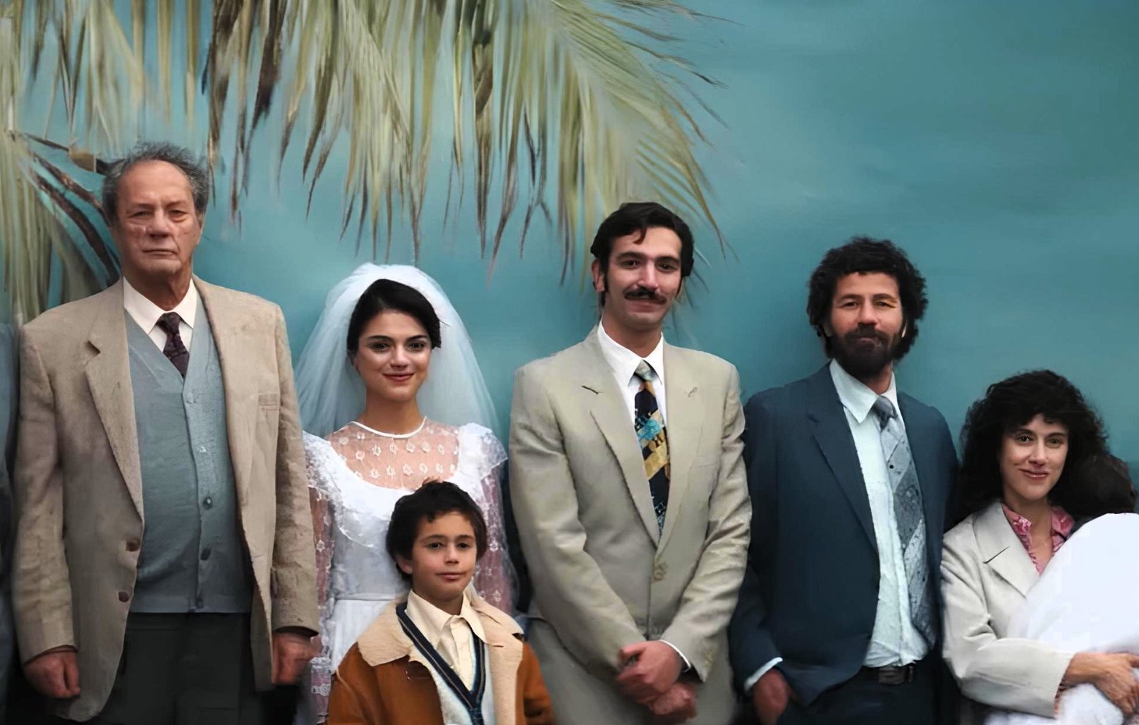 Una famiglia in posa per un matrimonio, sullo sfondo di una palma tropicale.