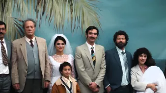 Una famiglia in posa per un matrimonio, sullo sfondo di una palma tropicale.