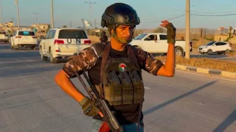 Un uomo in uniforme militare, con un fucile e un elmetto, si erge su una strada.