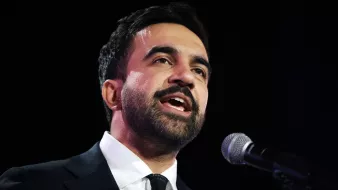 Uomo in giacca scura parla al microfono, esprime passione e coinvolgimento.