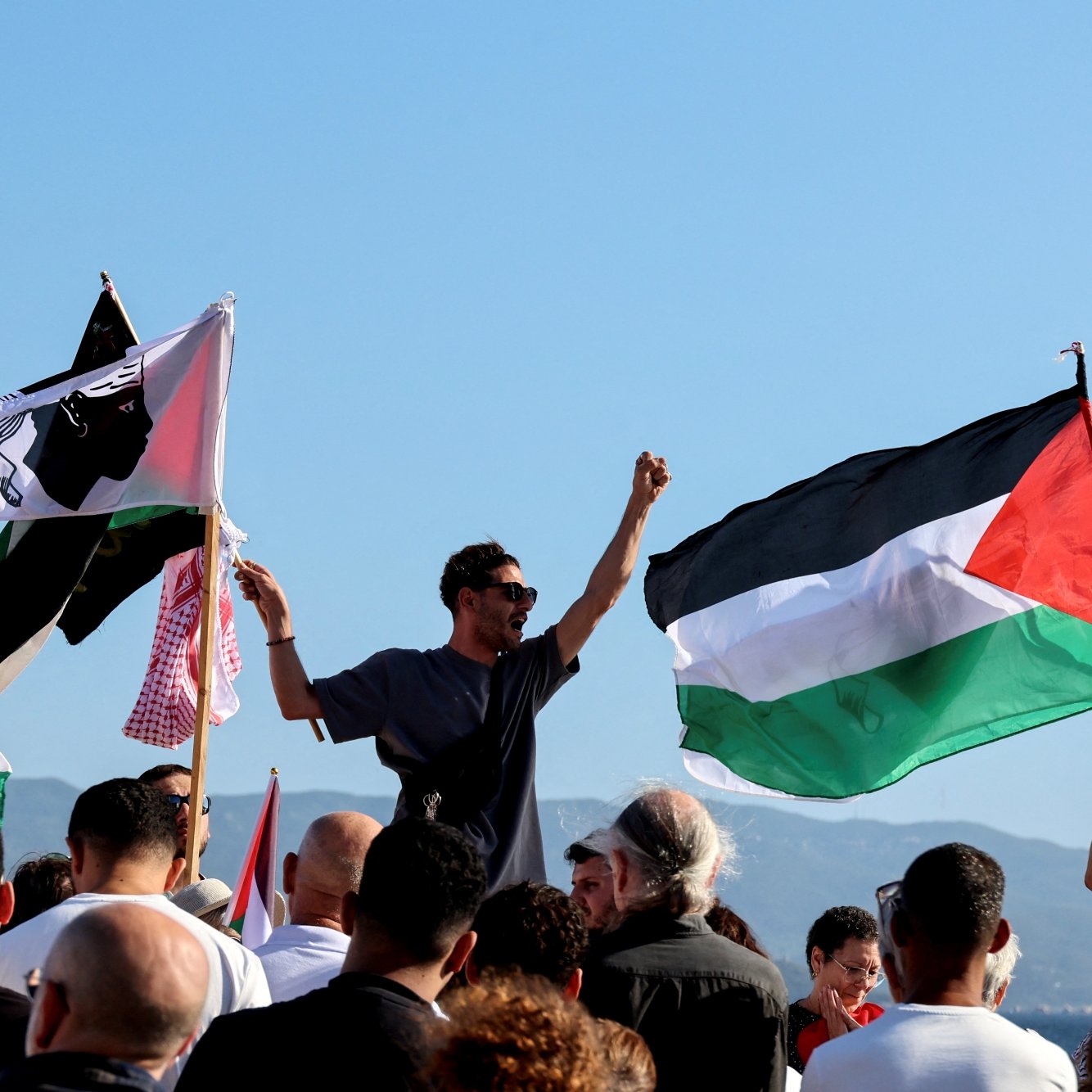 Manifestation avec des drapeaux palestiniens et des personnes rassemblées, exprimant leur soutien.