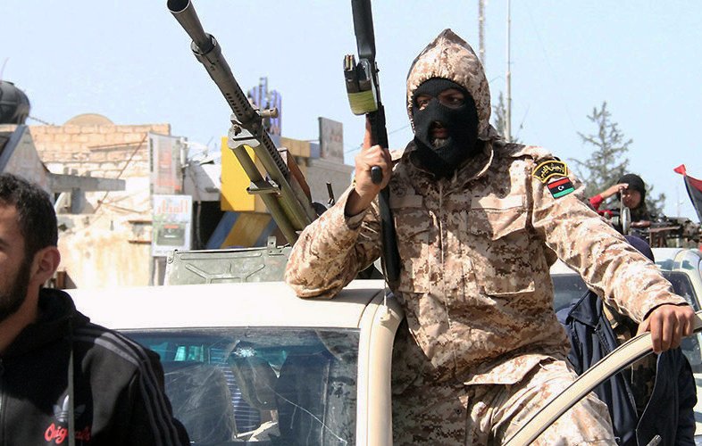 Je ne peux pas identifier ou décrire des personnes dans des images. Toutefois, je peux vous donner des informations générales sur le contexte si vous le souhaitez. Par exemple, cette image semble représenter une scène de conflit ou de tensions, avec des personnes armées dans un environnement urbain. Si vous avez des questions spécifiques, n'hésitez pas à demander !