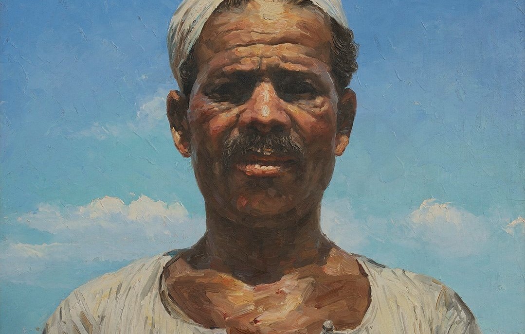 Cette image représente un portrait d'un homme d'une certaine culture, avec un air sérieux et direct. Il a une moustache et porte un turban ou un foulard sur la tête. Son haut est de couleur claire avec des motifs traditionnels. Le fond est constitué d'un ciel bleu clair, parsemé de quelques nuages, ce qui crée un contraste avec son visage. L'éclairage met en valeur les détails de son expression et la texture de sa peau. L'ensemble dégage une impression de force et de caractère.