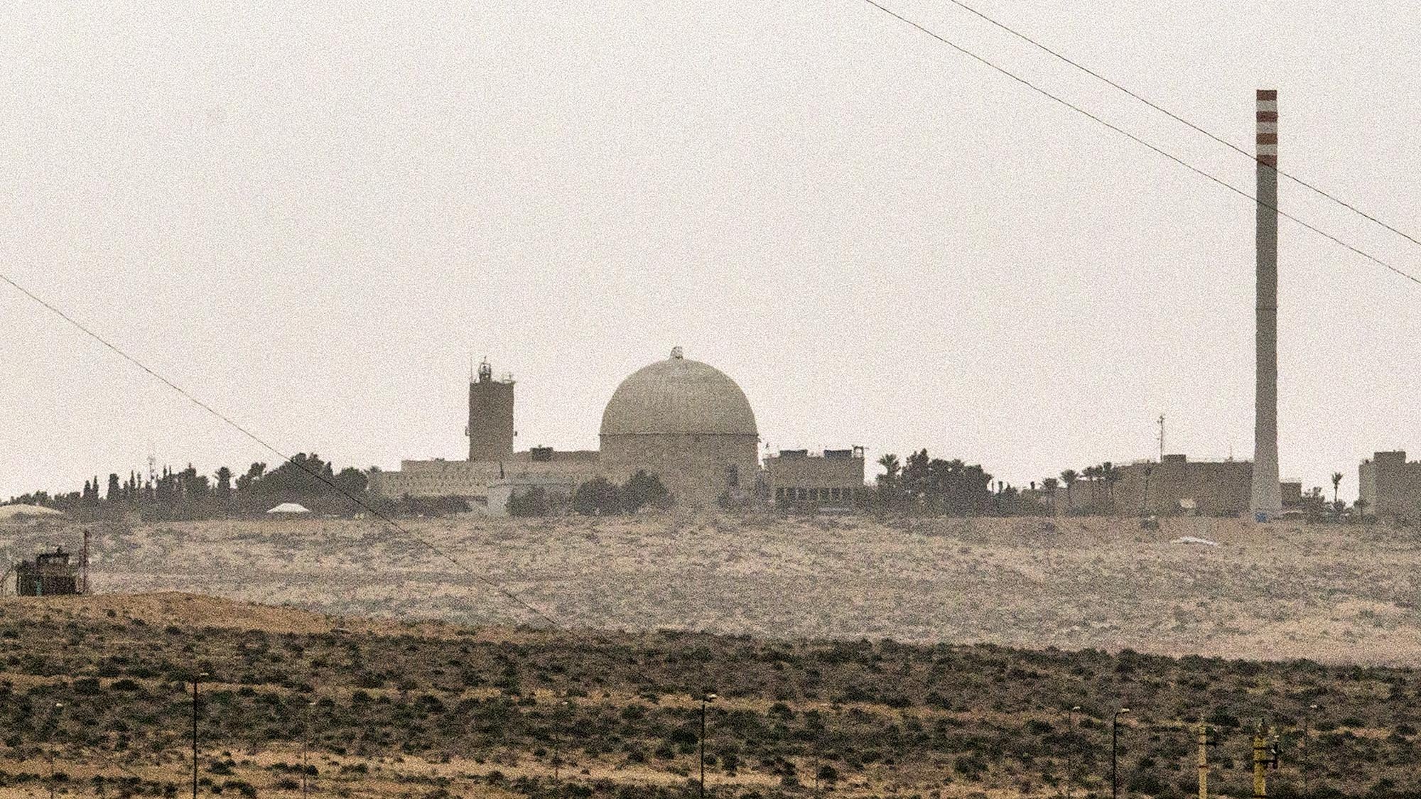 تصویر نمایی از یک تاسیسات صنعتی یا علمی را نشان می‌دهد که دارای یک گنبد بزرگ و چند ساختمان دیگر است. در سمت راست تصویر، یک دودکش بلند به چشم می‌خورد که ممکن است مربوط به فعالیت‌های صنعتی باشد. فضای اطراف تصویر سرسبز نیست و بیشتر به بیابان یا زمین‌های خشک مشابهت دارد. آسمان نیز ابری و کدر به نظر می‌رسد. این تصویر ممکن است به یک مرکز تحقیقاتی یا نیروگاه اشاره داشته باشد.