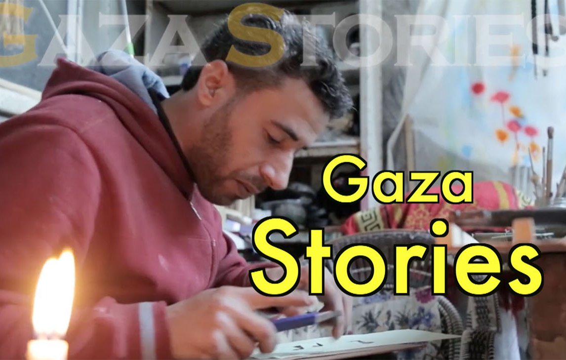 L'image montre un homme assis, probablement en train de travailler sur un projet créatif ou artisanal. Il porte un sweat à capuche rouge et semble concentré sur son activité. À côté de lui, une bougie est allumée, ce qui indique qu'il pourrait travailler dans un environnement peu éclairé. En arrière-plan, on aperçoit des éléments de décoration ou des fournitures, ce qui suggère une atmosphère artistique. En haut de l'image, on peut lire "Gaza Stories", ce qui laisse penser que le contexte est lié aux récits ou aux témoignages de Gaza.