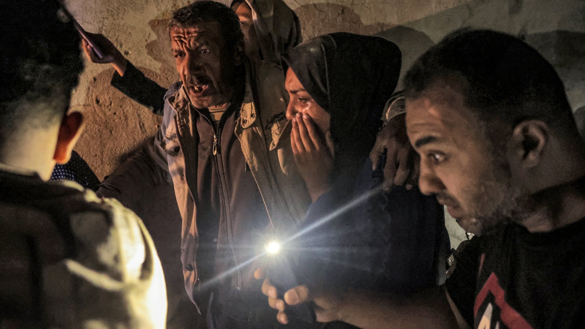 Un groupe de personnes dans une lumière tamisée, exprimant des émotions fortes.
