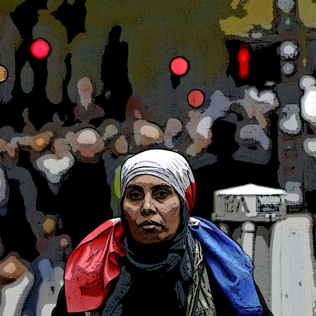 L'image représente une femme au premier plan portant un foulard et une écharpe aux couleurs bleu, blanc, rouge, qui symbolisent le drapeau français. En arrière-plan, on voit une foule floue, suggérant une atmosphère urbaine animée. Les lumières au loin ajoutent une touche de couleur à l'ambiance générale, offrant un contraste avec la concentration de la femme au centre de l'image.