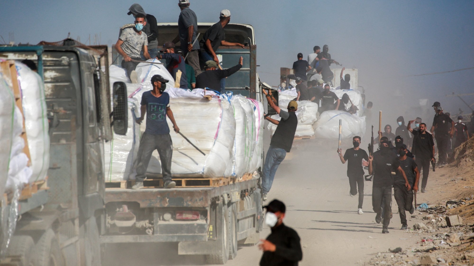 Des camions chargés de marchandises, des travailleurs en mouvement dans la poussière.