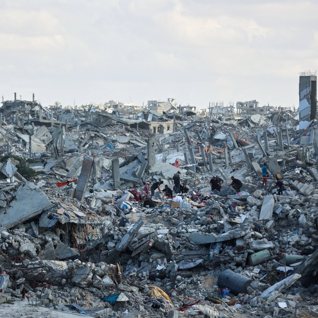 Destruction massive avec décombres et silhouettes humaines cherchant des survivants.