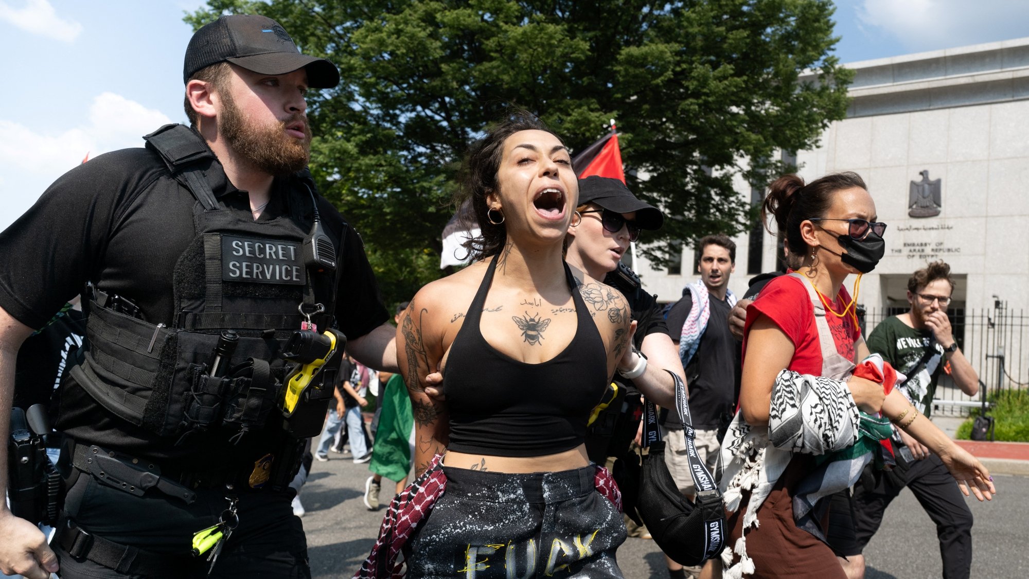 Manifestation intense avec des personnes interpellées par des agents de sécurité.