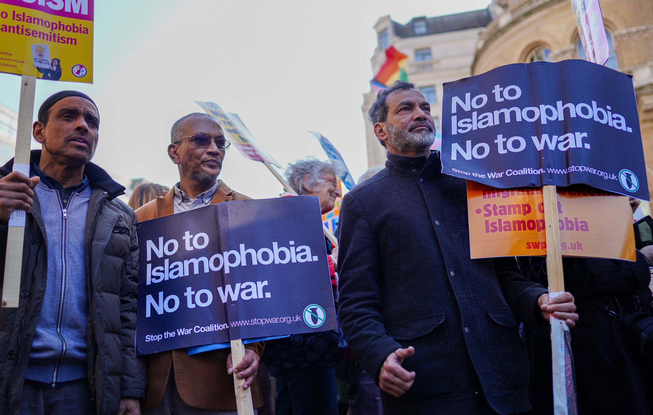 L'image montre un groupe de personnes participant à une manifestation. Elles tiennent des pancartes avec des messages clairs, notamment "No to Islamophobia. No to war." et "Stop the War Coalition". Les manifestants expriment leur opposition à l'islamophobie et à la guerre. On peut voir des personnes de divers âges et origines, toutes unies par leur cause. L'ambiance semble engagée et déterminée.