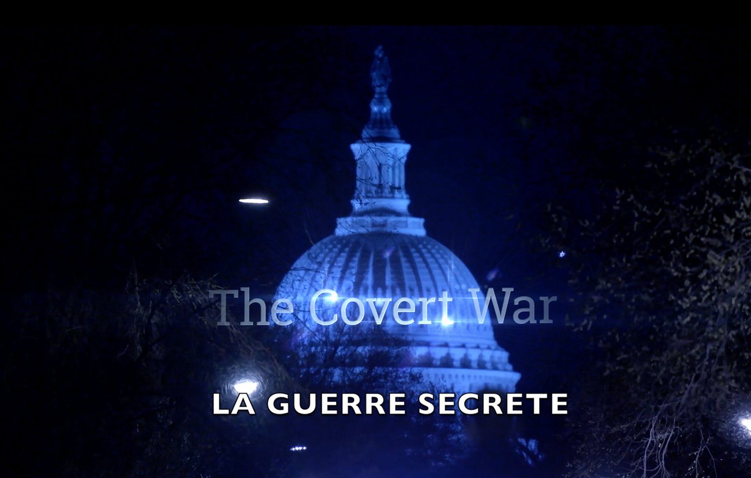 L'image montre un bâtiment emblématique, probablement le Capitole, illuminé de façon dramatique la nuit. En haut de l'image, on peut lire "The Covert War" en lettres blanches, tandis qu'en bas, le texte "LA GUERRE SECRETE" est affiché en plus grand, sur un fond sombre. L'éclairage crée une atmosphère mystérieuse et intrigante, suggérant un thème lié à la clandestinité ou aux opérations secrètes.