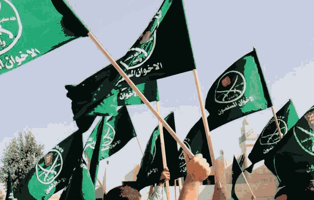 The image features a multitude of green flags being waved, likely during a rally or demonstration. The flags bear inscriptions and symbols, which may represent a specific political or ideological group. The overall atmosphere suggests a sense of unity and enthusiasm among the participants. The background may include people and structures, emphasizing the communal aspect of the event.