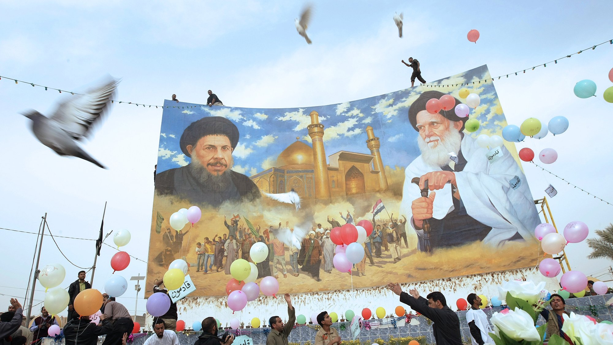 در این تصویر، تعدادی از مردم در حال برگزاری یک مراسم یا جشن هستند. در پس‌زمینه، یک دیوار بزرگ با تصویری از دو شخصیت سیاسی یا مذهبی به نمایش درآمده است. افراد در حال پرتاب بالن‌های رنگی و همچنین برخی گل‌ها به سمت هوا هستند. برخی از مردم در حال رقص و شادمانی دیده می‌شوند. پرنده‌هایی نیز در آسمان در حال پرواز هستند و فضای کلی تصویر روحیه مثبت و شادابی را به نمایش می‌گذارد.