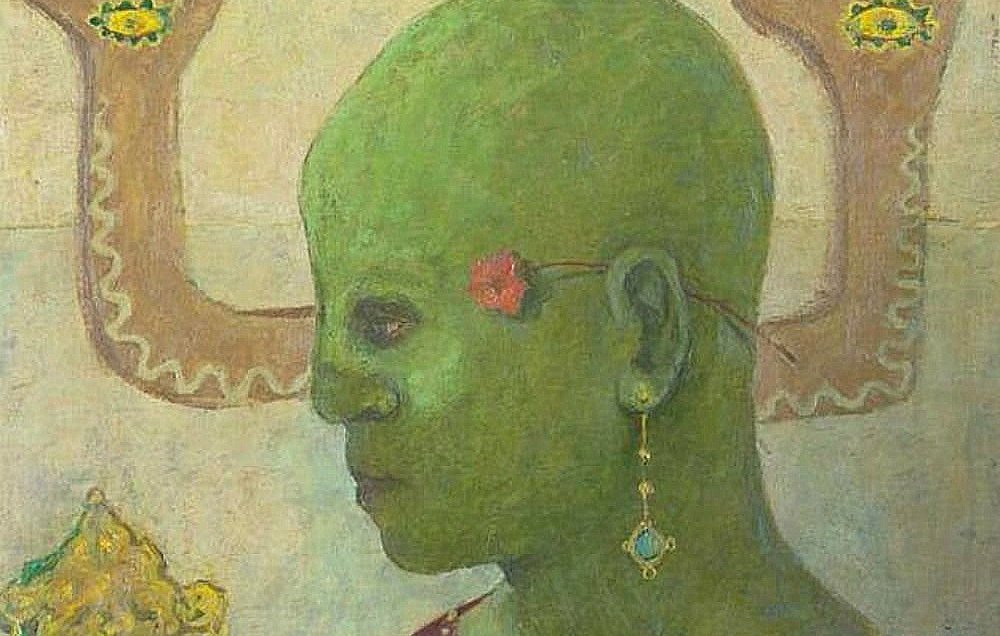 L'image montre un personnage avec une peau verte, une tête chauve et un regard contemplatif. Il porte une boucle d'oreille et une fleur rouge dans les cheveux. En arrière-plan, on voit deux mains qui semblent venir de derrière lui, ornées de motifs ou de décorations. Le personnage est habillé d'une tunique de couleur sombre. L'ensemble évoque une ambiance à la fois mystique et énigmatique, avec une palette de couleurs douce et des éléments symboliques.