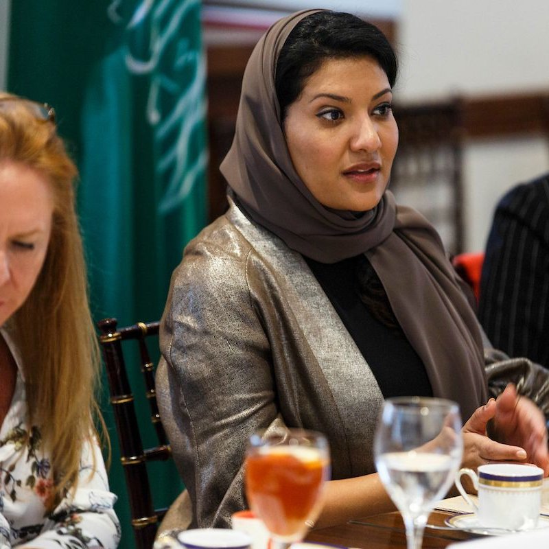 در این تصویر، یک جلسه یا گردهمایی در حال برگزاری است. در مرکز تصویر، زنی با حجاب و لباسی رسمی نشسته است و به صحبت کردن مشغول است. در سمت چپ، زنی دیگر با موی بلند و لباسی غیررسمی دیده می‌شود که به نظر می‌رسد به سمت صحبت کننده در حال گوش کردن است. در سمت راست، زنی دیگر با لباسی رسمی و لباس خط دار نشسته است. برخی از میوه‌ها و نوشیدنی‌ها روی میز قرار دارند و به نظر می‌رسد مهمانی یا جلسه‌ای دوستانه برگزار می‌شود. پس‌زمینه‌ی تصویر نیز نشان‌دهنده‌ی فضایی رسمی است.