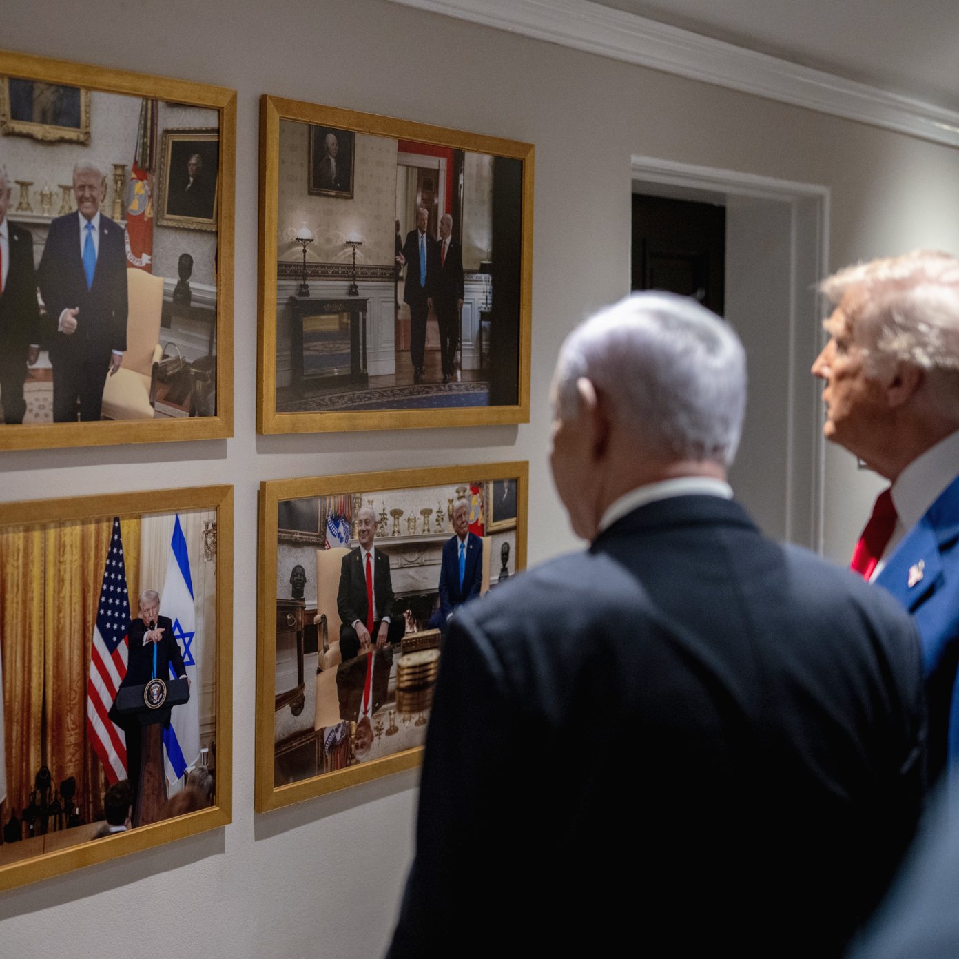 Des hommes politiques regardent des photos accrochées au mur, représentant des rencontres officielles.