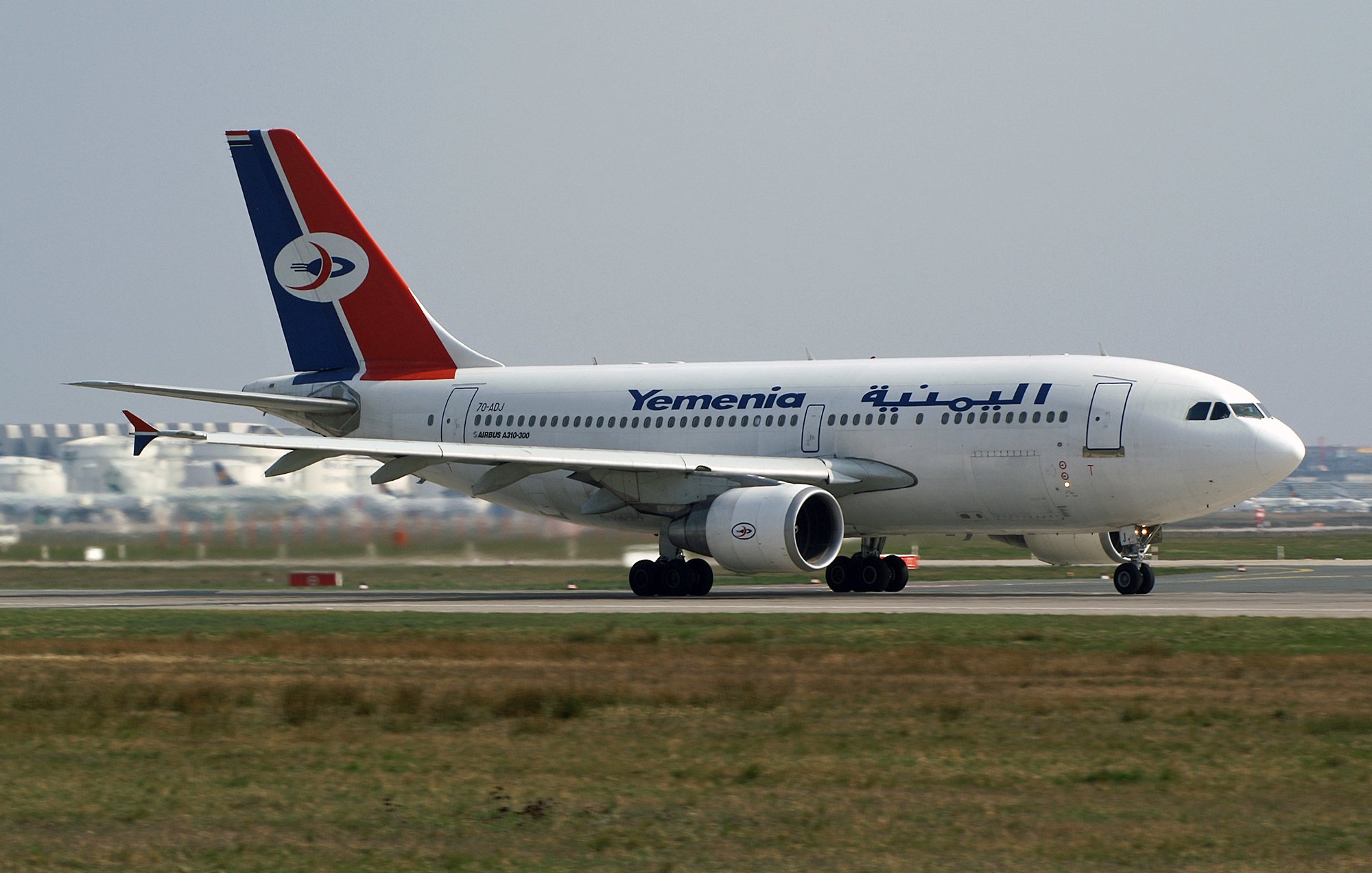 Avion de la compagnie Yemenia avec un design aux couleurs rouge, bleu et blanc sur la piste.