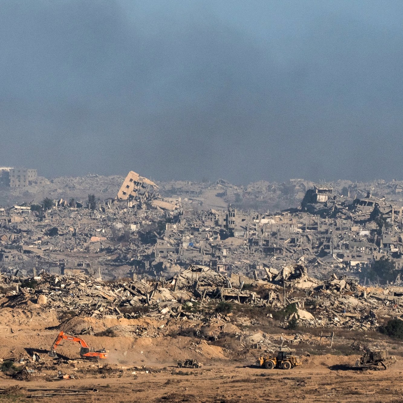 Terrain dévasté avec des bâtiments en ruines et des machines de chantier.